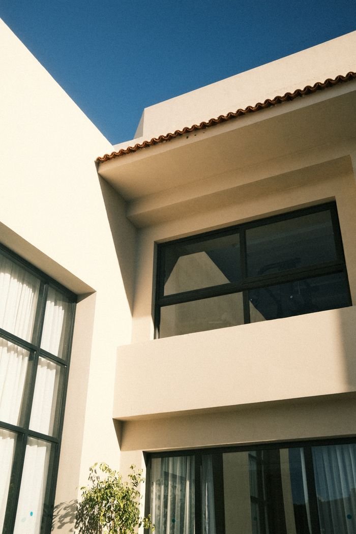 about-bg Elegant modern house exterior with large windows under clear blue sky.