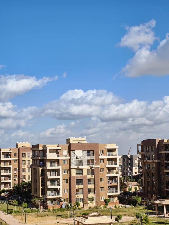 services-05 Contemporary apartment complex with bright blue sky and clouds.