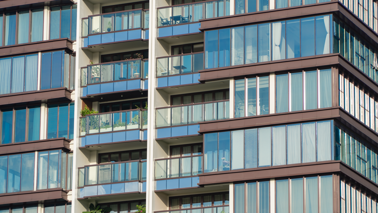 services-04 Close-up view of modern glass apartment facade with balconies and reflections.